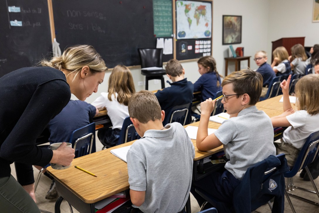 Teachers leans down to look at student's notes.