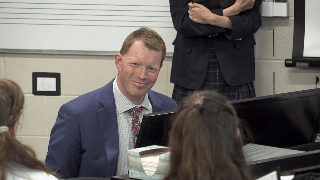 Music teacher pays piano in a classroom with students